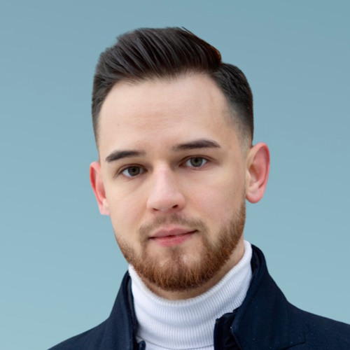 A Polish young man wearing a white turtleneck and black coat against the blue background.